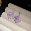 Vue détaillée des boucles d'oreilles en zircone rose sur un plateau à bijoux de velours - Rose