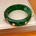 Primo piano dettagliato che mostra la trama marmorizzata verde e i rivetti dorati del bracciale. - Bracciale(HB6151) / Verde