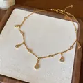 Dettaglio di una collana girocollo dorata minimalista con brillanti pendenti in zircone a goccia d'acqua - Oro (Placcato Oro)