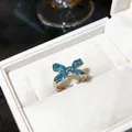Vista detallada de un anillo de mariposa plateado con circonitas azules en estuche - Estilo Geométrico de Racimo Azul