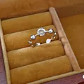 Close-up of silver-tone open ring with clear zircon in a yellow velvet box - Beaded Band Style / Silver