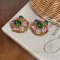 Close-up detail of vintage palace style earrings featuring enamel flowers and pearls. - Pink