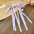 Detailed view of a sweet lavender ribbon bow hair clip with long tassels and pearl - Purple