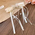 Close-up of elegant cream satin bow hair clip with crystal butterfly and lily pendants - White