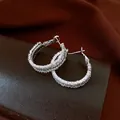 Dettaglio di orecchini a cerchio in argento con pavé di scintillanti zirconi bianchi. - Argento