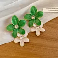 Close-up of green and white enamel flower earrings with sparkling rhinestone centers - Double Layer Flower / Green