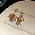 Dettaglio ravvicinato di orecchini a cuore champagne di lusso con accenti di cristallo - Marrone oro