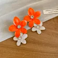 Close-up of vibrant orange and white enamel flower earrings with sparkling rhinestones - Double Layer Flower / Orange