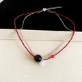 Primo piano dell'elegante collana a due strati con perline rosse e ciondolo a fiore. - Collana / Rosso Nero