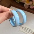 Close-up detail view of light blue spray-painted hoop earrings with a smooth glossy finish - Large / Blue