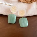 Close-up of frosted resin flower earrings with mint green square drop pendants on wood - Transparent White - Green (Silver Earring Post)