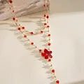 Close-up detail of a gold-tone necklace featuring vibrant red resin flowers and gems. - Red Floral (Double Layered) / Gold