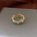 Elegant gold-plated open bangle featuring blue enamel flowers and white cat's eye stones - Ring / Gold-Blue