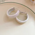 Close-up of white painted C-shaped hoop earrings on a decorative plate. - Small / White