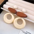 Close-up detail of retro resin and wood round pendant earrings in a jewelry box - Silver Earring Post Style / White Brown