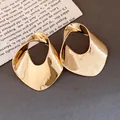 Primo piano di orecchini geometrici traforati in oro su sfondo di carta vintage - Stile Geometrico Tondo Traforato (HE34139) / Oro
