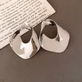 Dettaglio ravvicinato di orecchini a perno geometrici cavi in argento con design metallico ritorto - Stile Geometrico Tondo Traforato (HE34139) / Argento