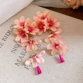 Détail macro de boucles d'oreilles pompons fleurs en tissu avec pétales roses - Rose