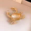 Detail showing the textured gold finish and pin closure of the crab brooch accessory. - Brooch / Gold