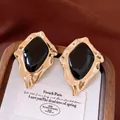 Vista dettagliata di orecchini geometrici vintage dorati con smalto nero in scatola. - Perno in argento - Oro - Nero