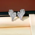 Gros plan de boucles d'oreilles cœurs étincelantes avec pavé de zircones sur support - Style Cœur Plaqué Or / Argent