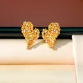 Gros plan sur les puces d'oreilles cœur plaqué or 18 carats avec pierres de zircone. - Style Cœur Plaqué Or / Or