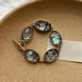 Dettaglio di un bracciale boho dorato con inserti ovali in conchiglia di abalone. - Oro-Blu