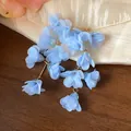 Close-up of light blue chiffon flower tassel earrings with elegant textured fabric background - Blue