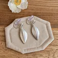 Dettaglio di orecchini a clip a forma di foglia argento opaco con gommini viola. - Orecchini a clip / Argento