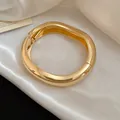 Primo piano di un bracciale rigido dorato lucido a forma di goccia su seta bianca. - Stile Semplificato a Goccia (5#)