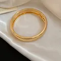 Dettaglio di un bracciale rigido in metallo dorato lucido con chiusura a scatto. - Cerniera Lucida Spessa (3#)