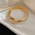 Vista dettagliata dell'elegante bracciale rigido dorato liscio con incrocio a goccia - Stile Incrociato Semplice (7#)