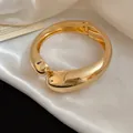 Vista dettagliata del bracciale rigido dorato a goccia incrociata su seta bianca lucida - Stile Incrociato a Goccia (1#)