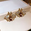 Close-up of luxury vintage gold-tone bee earrings with clear crystals and red stones - Silver Pin - Stud Earrings / Gold-Red