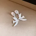 Close-up detail of silver-toned textured swallow-shaped drop earrings for women - Swallow Drop Earrings / Silver