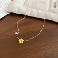 Close-up of silver-tone chain necklace with yellow flower pendant and zircon detail on wood - Silver-Yellow