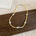 Dettaglio ravvicinato di una collana di perline colorate a fiori su base in legno - Bianco Giallo Arancione e Verde