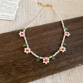 Dettaglio di una collana di perline bianche fatta a mano con ciondoli a fiori - Bianco e Rosso