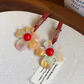 Nahaufnahme von marmorierten Blumen-Haarklammern mit rotem Zentrum auf roter Metallbasis - Entenschnabel-Clip (Rot) / 1 Stück / bunt