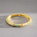 Close-up of gold-plated bangle with colorful enamel floral patterns and crystals - Pink-Cyan
