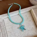 Detailed macro shot of a blue beaded vacation necklace with a glass starfish pendant - Green