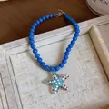 Close-up detail of a blue beaded necklace featuring a vibrant dotted glass starfish pendant - Blue