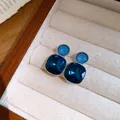 Close-up detail of elegant deep blue square and light blue round crystal earrings - Silver-Blue