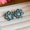 Close-up detail of vibrant colorful glass flower stud earrings on beige jewelry box - Olive Green