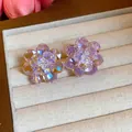 Detail view of shimmering purple glass flower stud earrings presented in a jewelry box - Pink