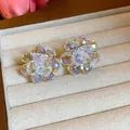 Macro detail of sparkling iridescent crystal flower stud earrings in a beige jewelry box - White