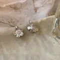 Vue macro détaillée de boucles d'oreilles en argent aux pétales froissés fleuris. - Argent