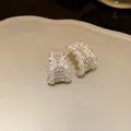 Close-up detail of C-shaped silver earrings with sparkling rhinestone encrustation - Silver