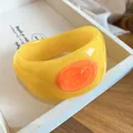 Macro view of a bold yellow resin bangle with orange swirled enamel texture detail - Yellow