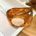Detail van vintage amberhars bangle met gemarmerde textuur en crème-kleurig inlay - Bruin